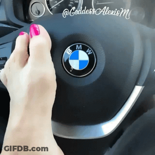 A Woman 'S Feet Are On The Steering Wheel Of A Bmw Car GIF