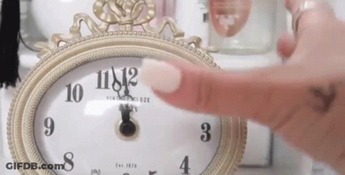 A Woman 'S Finger Is Pointing At A Clock That Shows The Time As 11:42 GIF