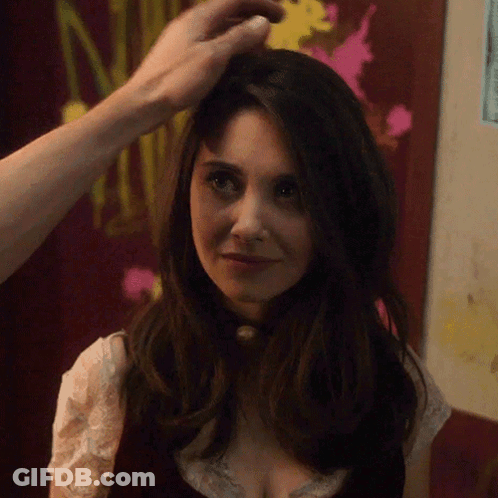 A Woman 'S Hair Is Being Touched By A Man In Front Of A Sign That Says N. GIF