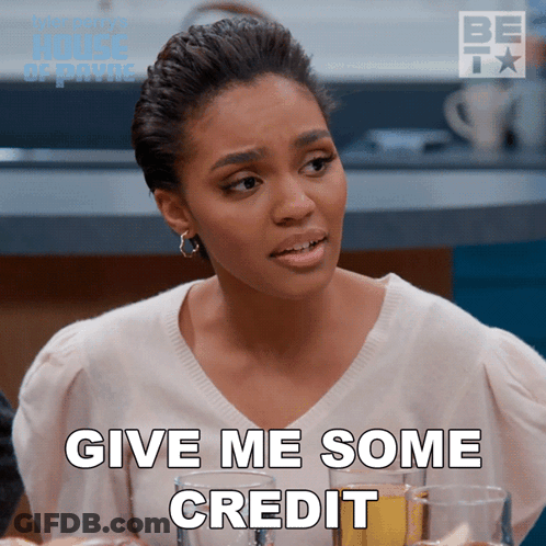 A Woman Says Give Me Some Credit While Sitting At A Table With Champagne Glasses GIF