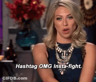 A Woman Says Hashtag OMG Insta-Fight In Front Of A Vase Of Flowers GIF