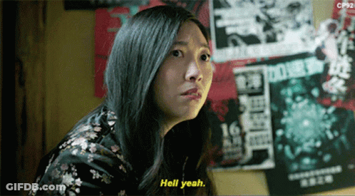 A Woman Says Hell Yeah In Front Of A Wall With Posters On It GIF