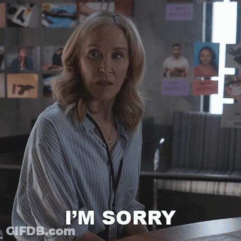 A Woman Says I 'M Sorry While Standing In Front Of A Desk GIF
