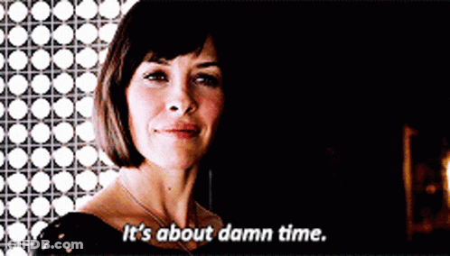 A Woman Says " It 'S About Damn Time " In A Dark Room GIF