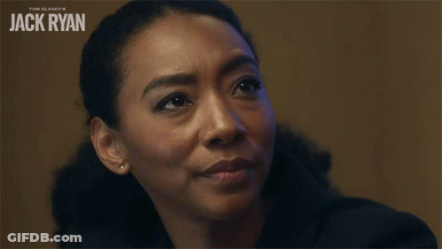 A Woman Says Meaning In Front Of A Jack Ryan Poster GIF