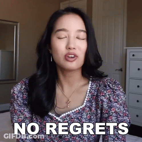 A Woman Says " No Regrets " In Front Of A Mirror GIF
