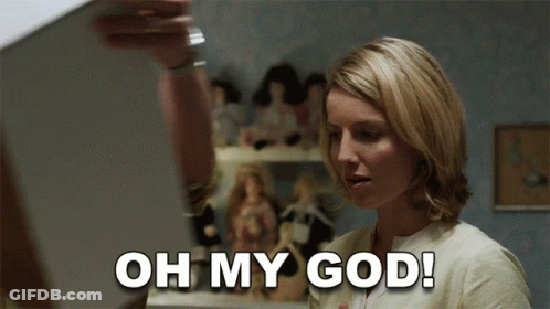 A Woman Says Oh My God In Front Of A Display Of Dolls GIF