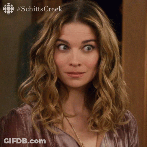 A Woman Says Sorry In Front Of A Picture Of Schitts Creek GIF
