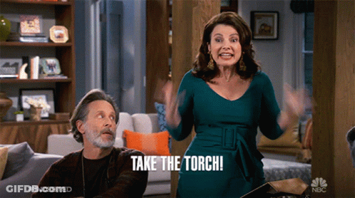 A Woman Says Take The Torch While A Man Looks On GIF
