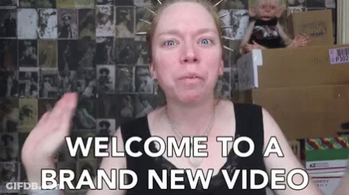 A Woman Says Welcome To A Brand New Video In Front Of Boxes GIF