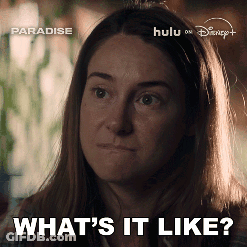 A Woman Says " What 'S It Like " In Front Of A Poster For Paradise GIF