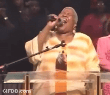 A Woman Singing Into A Microphone At A Podium GIF