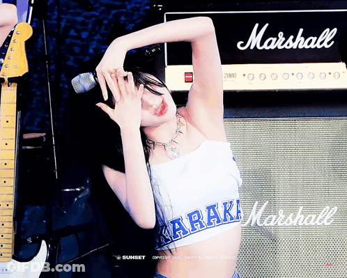 A Woman Singing Into A Microphone In Front Of A Marshall Amp GIF