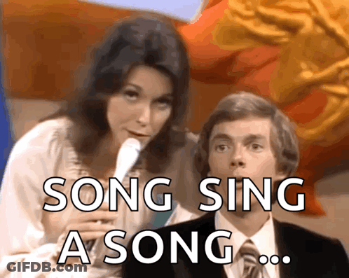 A Woman Singing Into A Microphone Next To A Man With The Words Song Sing A Song GIF