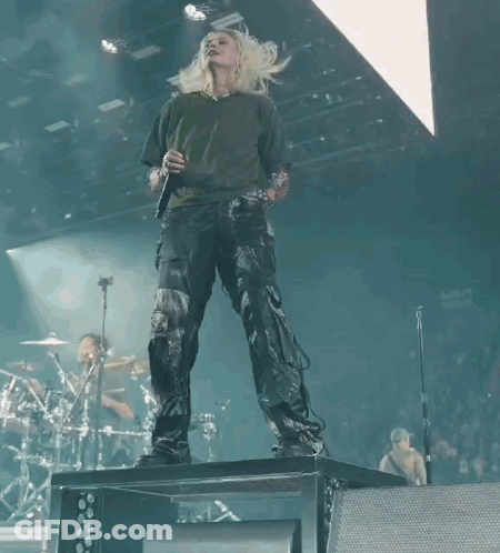 A Woman Singing Into A Microphone On Stage GIF