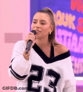 A Woman Singing Into A Microphone Wearing A Jersey With The Number 23 On It GIF
