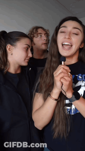A Woman Singing Into A Microphone Wearing A Shirt That Says Cc On It GIF