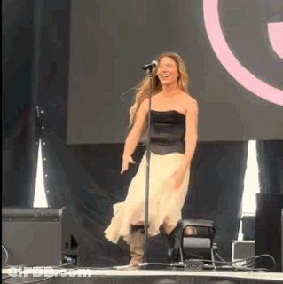 A Woman Singing Into A Microphone While Dancing On Stage GIF