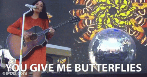 A Woman Singing Into A Microphone While Holding A Guitar With The Words " You Give Me Butterflies " On The Bottom GIF