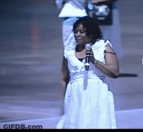 A Woman Singing Into A Microphone While Wearing A White Dress GIF