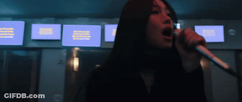 A Woman Singing Into A Microphone With A Blue Screen Behind Her That Says ' Netflix ' On It GIF