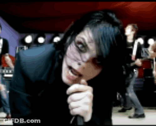 A Woman Singing Into A Microphone With A Group Of People Behind Her GIF