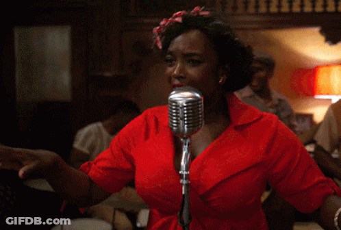 A Woman Singing Into A Microphone With A Red Shirt On GIF