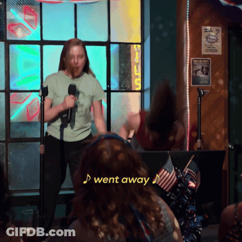A Woman Singing Into A Microphone With A Sign That Says I Went Away GIF