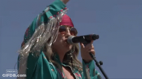 A Woman Singing Into A Microphone With A Sign That Says Stagecoach On It GIF