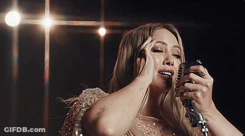 A Woman Singing Into A Microphone With A Tattoo On Her Arm That Says " I Love You " GIF