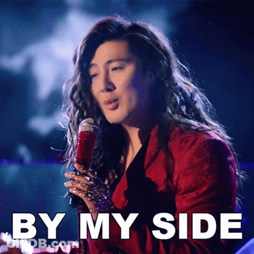 A Woman Singing Into A Microphone With By My Side Written Below Her GIF