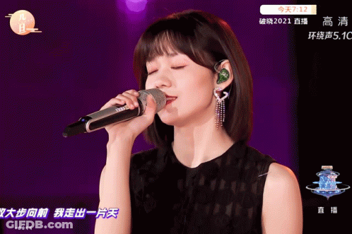 A Woman Singing Into A Microphone With Chinese Writing On The Bottom GIF