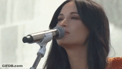 A Woman Singing Into A Microphone With Her Eyes Closed . GIF