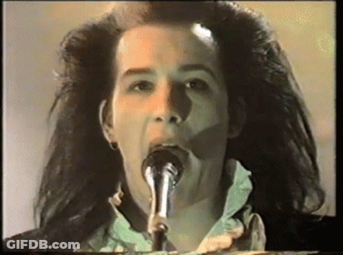 A Woman Singing Into A Microphone With Her Mouth Open GIF