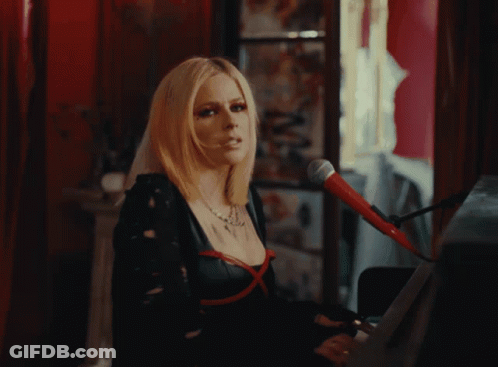A Woman Singing Into A Microphone With Red Eye Shadow GIF