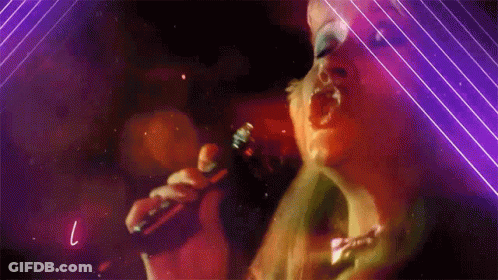 A Woman Singing Into A Microphone With The Letter L Visible GIF