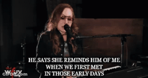 A Woman Singing Into A Microphone With The Words " He Says She Reminds Him Of Me " GIF