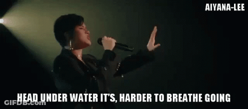 A Woman Singing Into A Microphone With The Words " Head Under Water It 'S Harder To Breathe Going " GIF