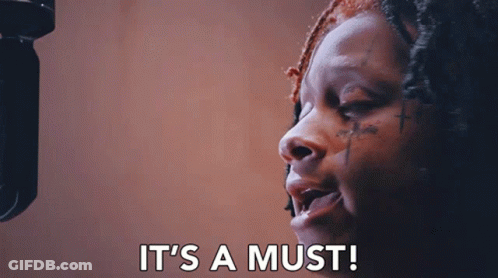 A Woman Singing Into A Microphone With The Words " It 'S A Must " Written Below Her GIF