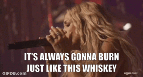 A Woman Singing Into A Microphone With The Words It 'S Always Gonna Burn Just Like This Whiskey Below Her GIF