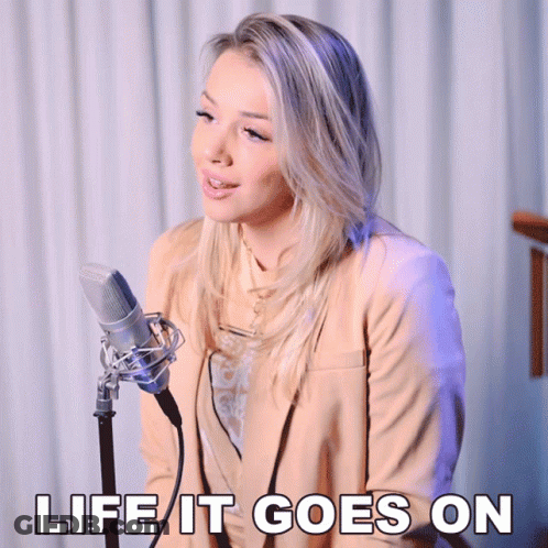 A Woman Singing Into A Microphone With The Words " Life It Goes On " Above Her GIF