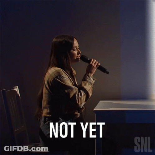 A Woman Singing Into A Microphone With The Words " Not Yet " Below Her GIF