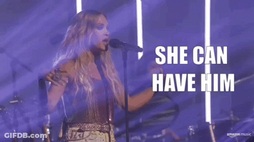 A Woman Singing Into A Microphone With The Words " She Can Have Him " Behind Her GIF