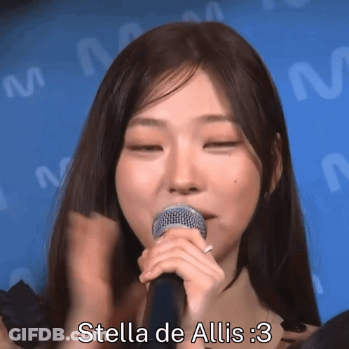 A Woman Singing Into A Microphone With The Words Stella De Allis : 3 Written Below Her GIF