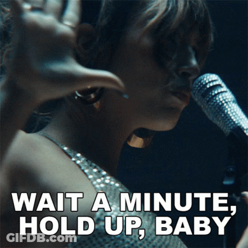 A Woman Singing Into A Microphone With The Words " Wait A Minute Hold Up Baby " Below Her GIF