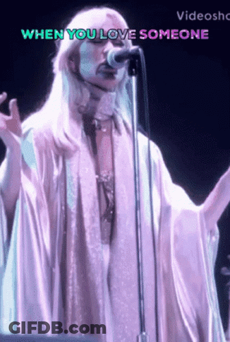 A Woman Singing Into A Microphone With The Words When You Love Someone Behind Her GIF