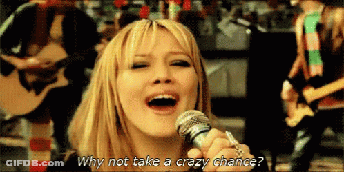 A Woman Singing Into A Microphone With The Words Why Not Take A Crazy Chance Written Below Her GIF