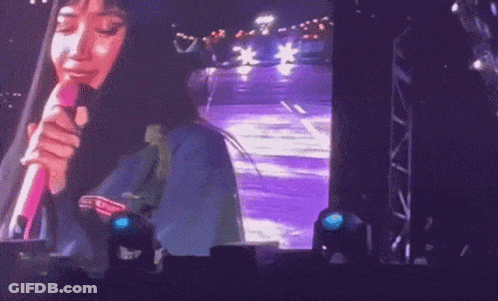 A Woman Singing Into A Pink Microphone On Stage GIF
