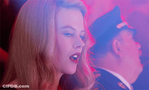 A Woman Singing With A Man In A Police Hat In The Background GIF