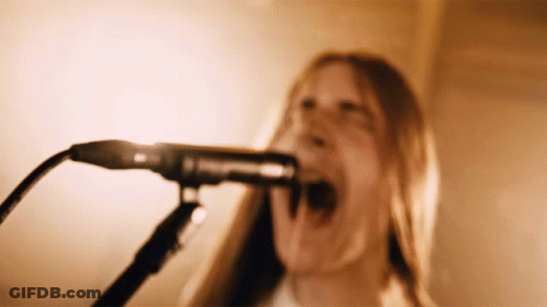 A Woman Sings Into A Microphone With Her Mouth Open GIF